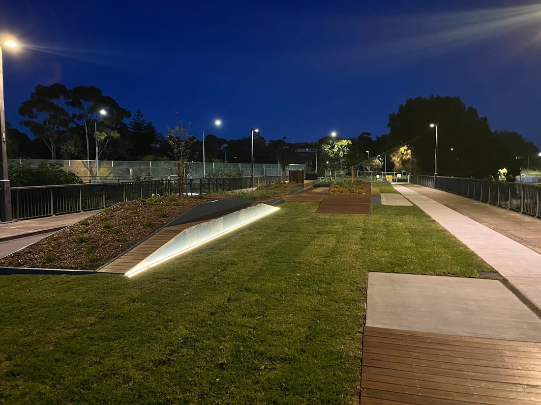Lit Bay Run precinct at dusk with feature ground lighting and path poles