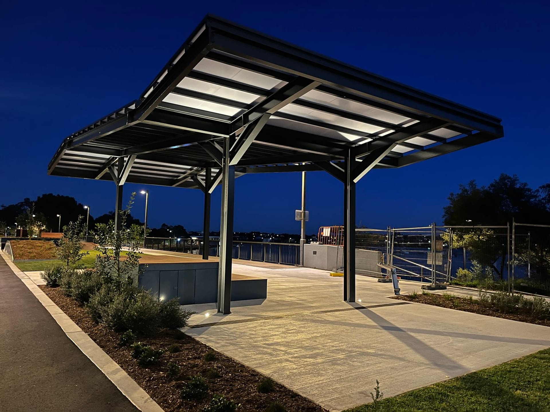 Illuminated shelter pavilion lit at twilight on the Bay Run foreshore
