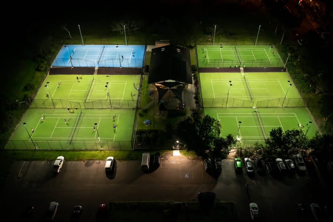 Overhead drone view of the illuminated Collaroy Tennis Club courts at night