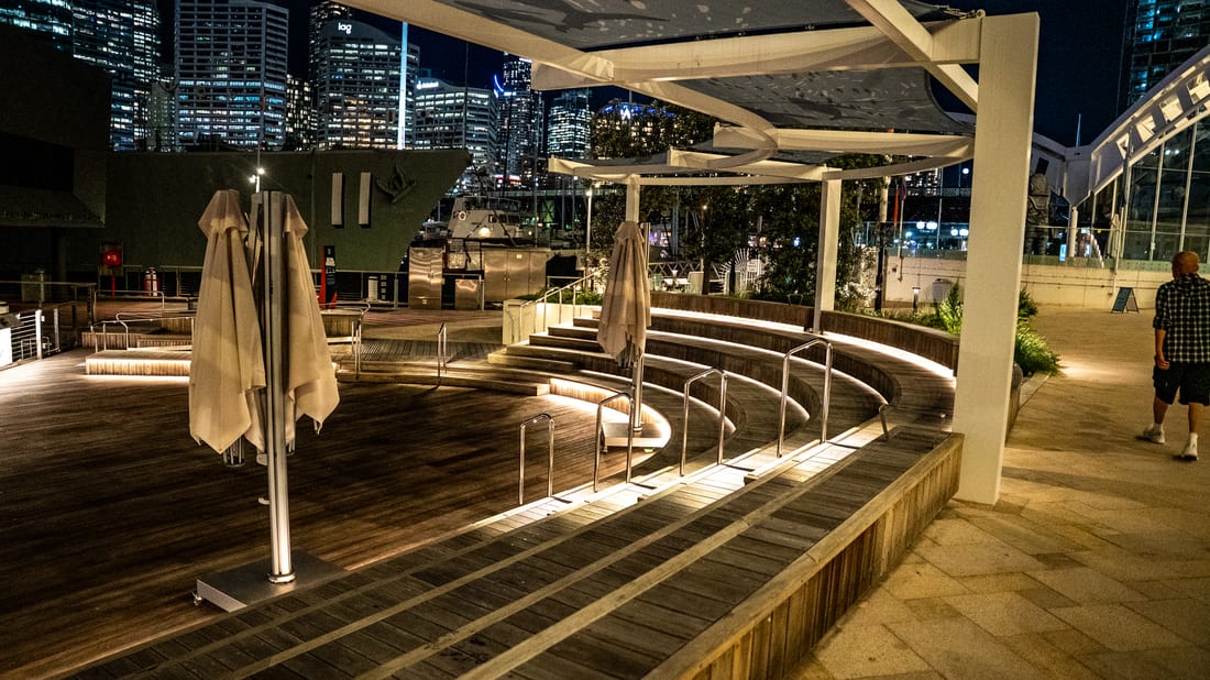 Illuminated curved timber terrace and shade structure at the Maritime Museum waterfront after dark