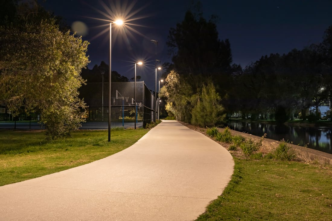 Lit park path beside the water at Richard Murden Reserve after dark