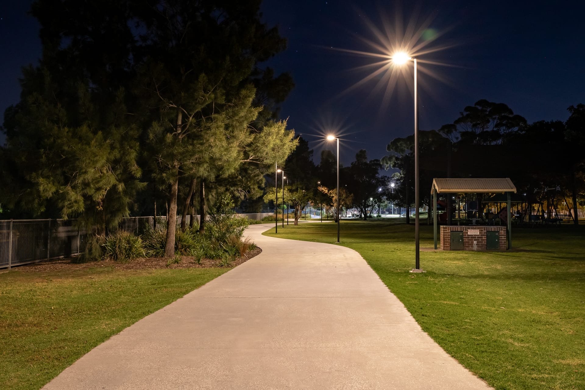 Floodlit shared pathway through Richard Murden Reserve at night, picnic shelter alongside