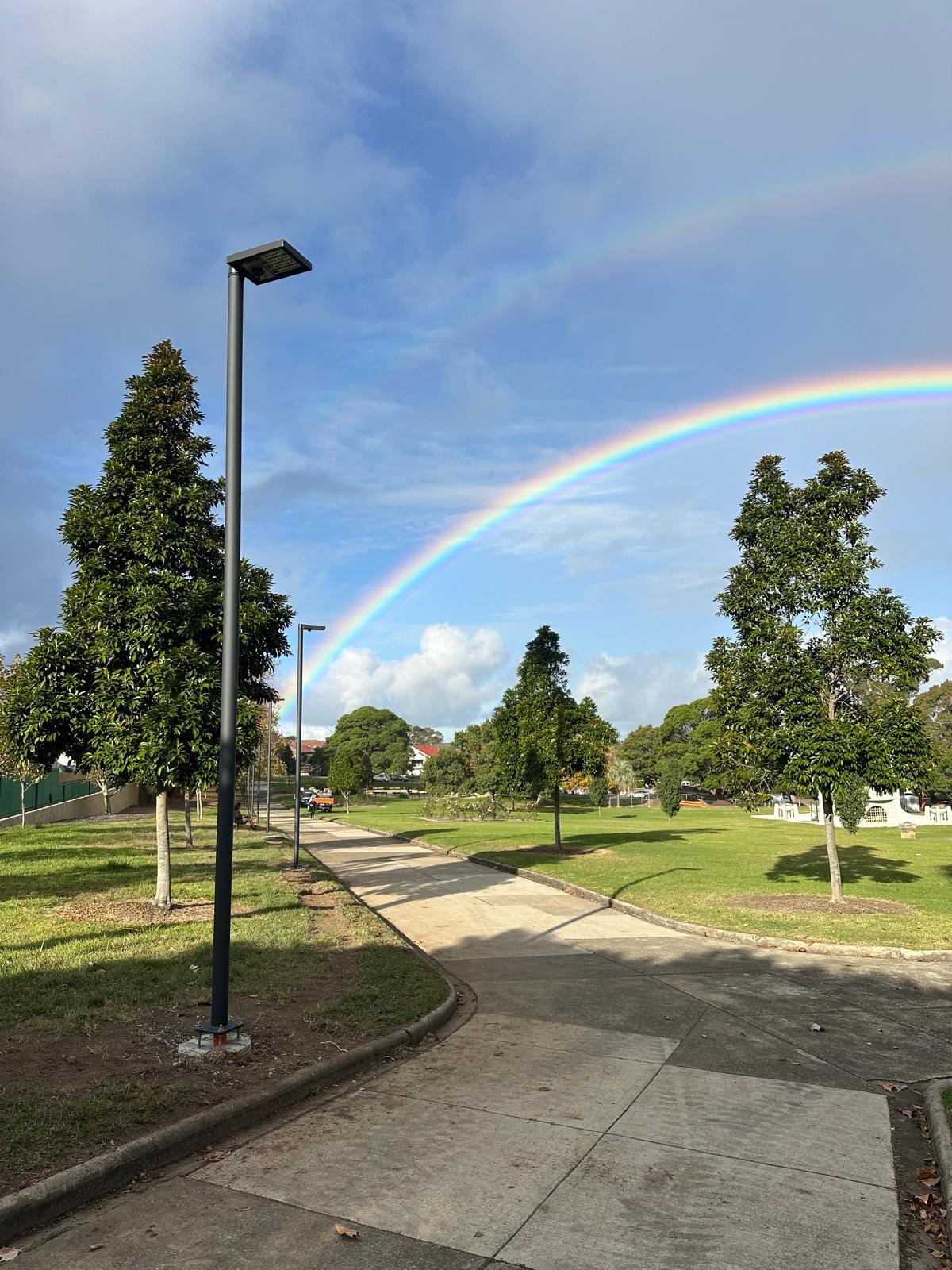 New park lighting pole on the path at Yeo Park, Ashfield, with a rainbow overhead